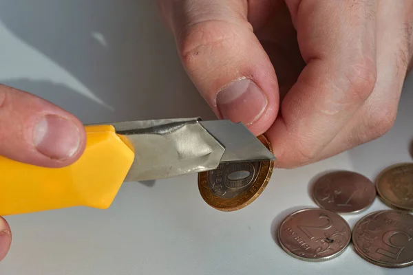 A man counts money and divides it. Round coins. Cutting of money with a knife
