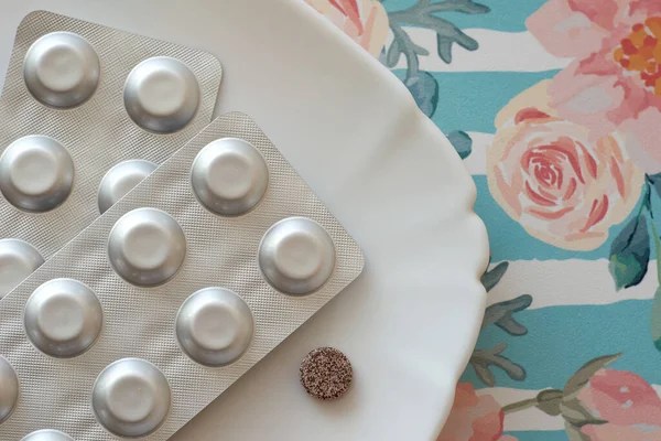 Tabakta demir haplar. Bir sürü demir sülfat tableti. Demir Eksikliği Anemi için ilave kullanım. Çiçek retro arka planı. Pastel rengi.