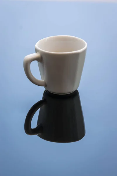 Yansımalı beyaz kahve fincanı. Açık hava fotoğrafçılığı. Mavi gökyüzünün rengi görünür. Çerçeve simetrik. 