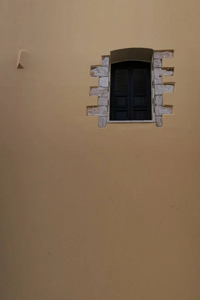 Pürüzsüz bej duvarda metal parmaklıklı pencere..