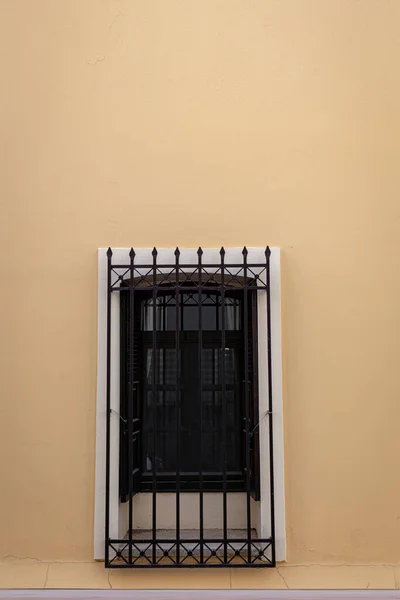 Pürüzsüz bej duvarda metal korkuluklu pencere. Asgari fotoğrafçılık.