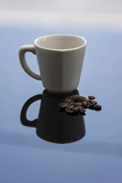 Una Pequeña Taza Café Blanco Una Superficie Vidrio Con Granos —  Fotos de Stock