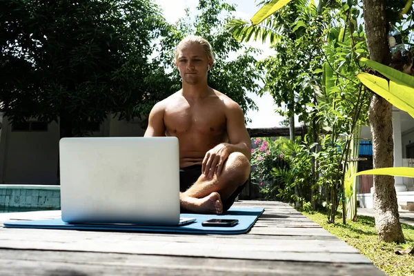 handsome man working with laptop computer at the poolside