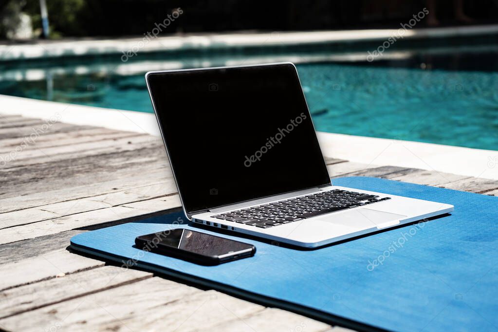 laptop and smartphone near swimming pool 