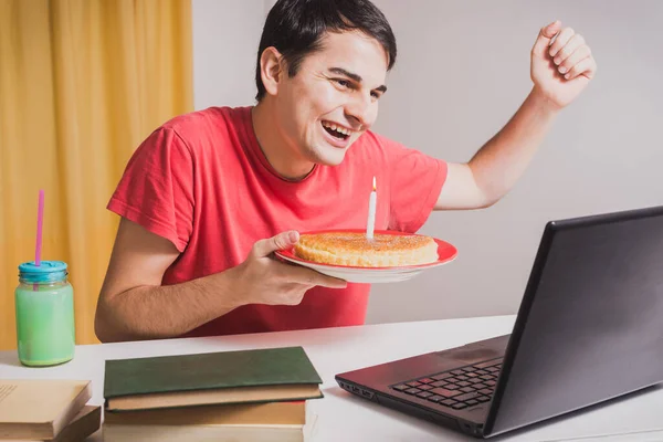 Happy young man celebrating his birthday party in quarantine. Family video call. Social distancing due to coronavirus. Smiling man celebrating his birthday by video conference from home. Life at home