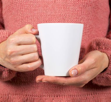 Kadın eli bardağı tutuyor.