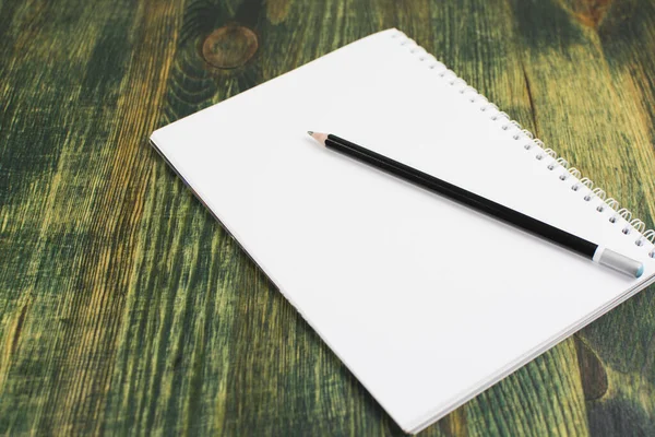 Yeşil masanın üzerinde siyah bir kalem olan beyaz bir çarşaf.