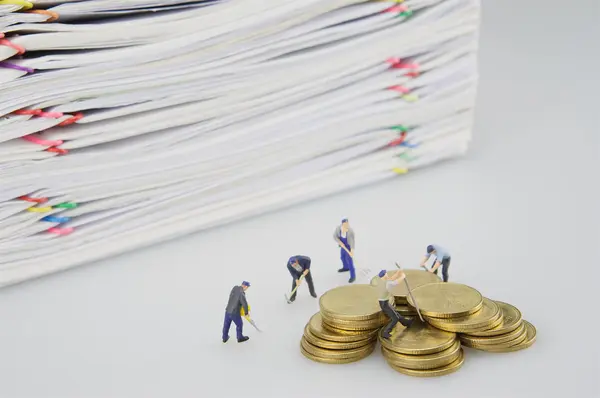 Personas en miniatura y documento de sobrecarga de pila con monedas de oro — Foto de Stock
