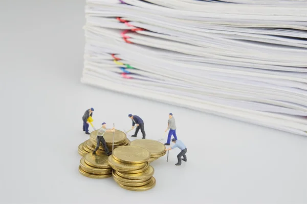 Personas en miniatura con monedas de oro y documento de sobrecarga de pila — Foto de Stock