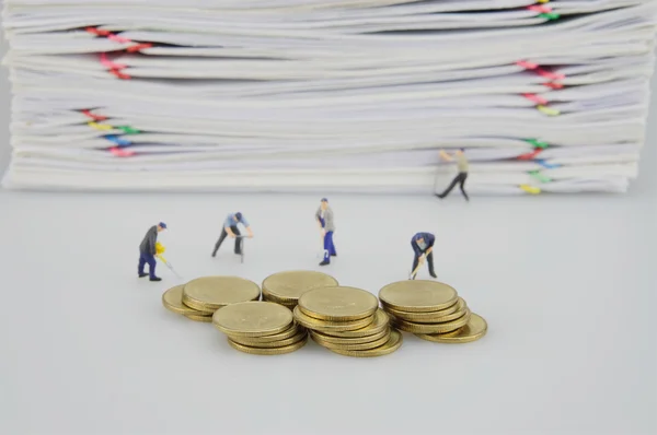 Documento de sobrecarga de pila y monedas de oro con personas en miniatura — Foto de Stock