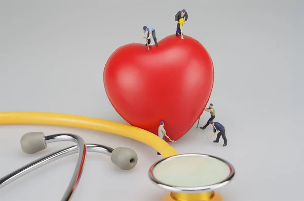 Personas en miniatura con corazón rojo y estetoscopio —  Fotos de Stock