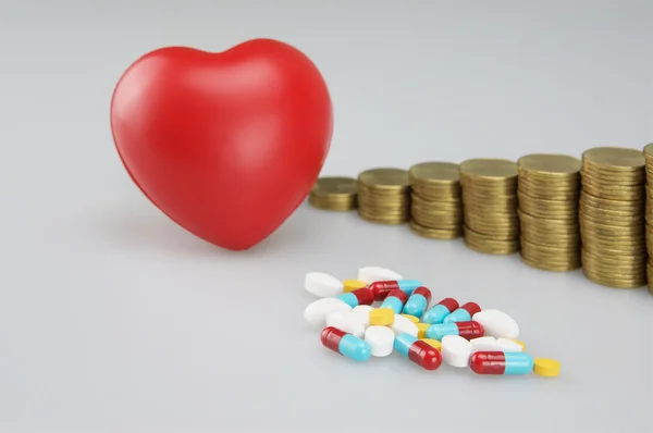 Pila de medicina y corazón rojo con monedas de oro — Foto de Stock