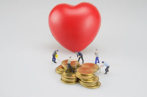 Montones de monedas con corazón rojo y miniatura — Foto de Stock