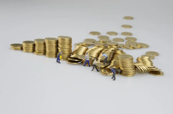 Montones de monedas y personas en miniatura — Foto de Stock