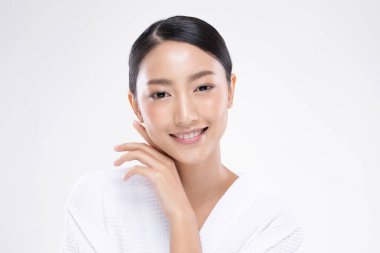 Güzel Asyalı kadın yumuşak yanaklı gülüşüne dokunuyor. Temiz ve taze tenli. Mutluluk ve neşe, olumlu duygusal, beyaz arka planda izole edilmiş.