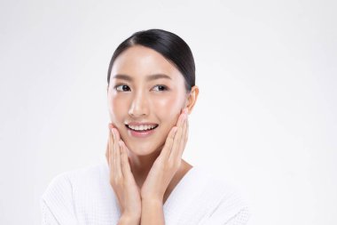 Güzel Asyalı kadın yumuşak yanaklı gülüşüne dokunuyor. Temiz ve taze tenli. Mutluluk ve neşe, olumlu duygusal, beyaz arka planda izole edilmiş.