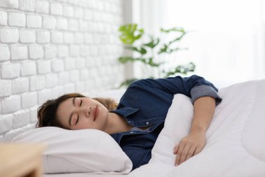 Pijama giyen güzel Asyalı kadın gözlerini kapar, gülümser ve tatlı rüyalar görür. Sabah yatak odasında rahat ve rahat hisseder. Sağlık ve Uyku Konsepti.
