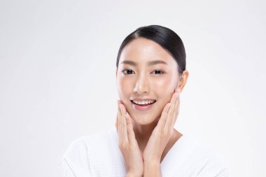 Güzel Asyalı kadın yumuşak yanaklı gülüşüne dokunuyor. Temiz ve taze tenli. Mutluluk ve neşe, olumlu duygusal, beyaz arka planda izole edilmiş.