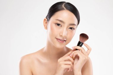 Güzel Asyalı genç kadın gülümseyecek ve makyaj fırçasıyla sağlıklı temiz ve taze bir ten hissedecek çok mutlu ve neşeli, beyaz arka planda izole edilmiş, güzellik kozmetik konsepti