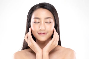 Güzel Asyalı kadın yumuşak yanaklı gülüşüne dokunuyor. Temiz ve taze tenli. Mutluluk ve neşe, olumlu duygusal, beyaz arka planda izole edilmiş.