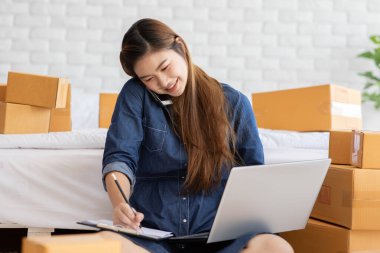 Evde online alışveriş için dizüstü bilgisayarla çalışan genç Asyalı kadınların KOBİ girişimcisi ve müşteriyle teslimat siparişi, Business Online ve Online alışveriş için Kendi İş Kuruluşu 