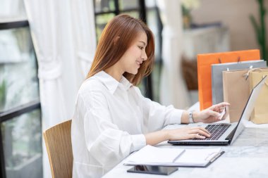 Güzel Çekici Asyalı kadın çevrimiçi alışveriş için kredi kartını kullanıyor çevrimiçi ödemeye dönüşüyor. Keyif ve mutluluk, alışveriş kavramı.