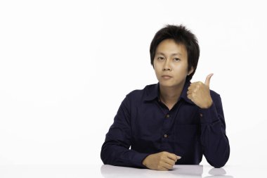 Asyalı yakışıklı, mavi gömlekli, rahat bir şekilde masada oturan, kendinden emin ve mutlu, beyaz arka planda soyutlanmış, Asyalı bir adam.