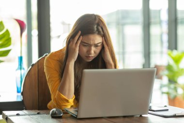 İş kadını Asyalı kadının migreni var. Bu yüzden baş ağrısı ve stresin iş yerinde ve ofis sendromu ile ilgili sorunları var.