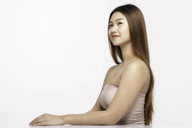 Güzel Asyalı Kadın Bakışları Çene 'ye dokunurken Uzaklara Bakıyor. Mutlu ve neşeli, sağlıklı, temiz ve taze tenli, beyaz arka planda soyutlanmış Güzellik Kozmetolojisi kavramı.