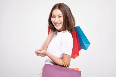 Kısa saçlı, gülümseyen ve alışveriş torbaları tutan neşeli ve mutlu Asyalı bir kadın, kara Cuma indiriminde alışverişin keyfini çıkar, gri arka planda izole edilmiş, alışveriş kavramı...