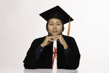 Mezuniyet gününde sertifikalı ya da diplomalı Asya mezunu bir adam, beyaz arka planda, eğitim alanında izole edilmiş, gururlu ve mutlu.