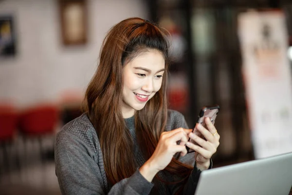 コーヒーショップカフェでスマートフォンを使用して美しい魅力的なアジアのビジネス女性の笑顔と幸福 暖かいトーン — ストック写真