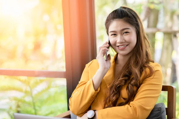 ビジネスアジアの若い女性がノートパソコンの笑顔で仕事をし コーヒーショップでオフィス外での成功のためのアイデアや要件を得るためにスマートフォンで顧客と話をする 中小企業のスタートアップコンセプト — ストック写真