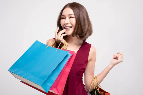 赤のドレスを着た短い髪の笑顔を持つショッピングアジアの女性ショッピングバッグを保持 陽気と幸福は黒の金曜日の販売で買い物を楽しむ 灰色の背景に隔離された — ストック写真