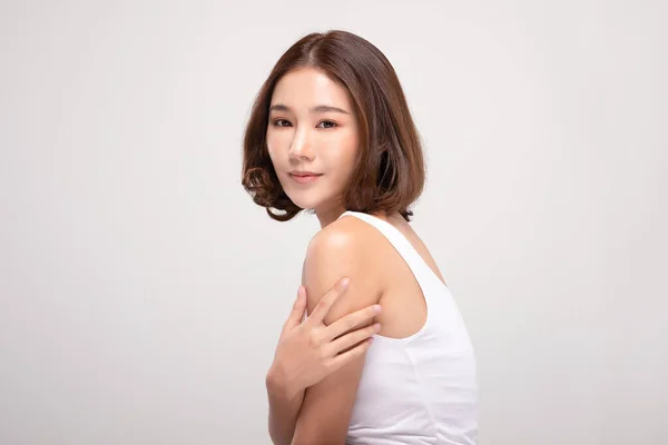 美丽的年轻亚洲女人 摸着肩膀 快乐而快乐 有着健康的洁净而新鲜的皮肤 有着灰白的背景 美容美感 — 图库照片