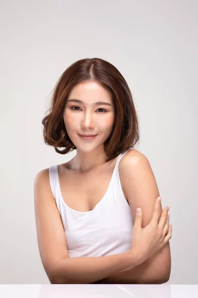 短い髪を持つ美しい若いアジアの女性は 灰色の背景に隔離された健康的な清潔で新鮮な肌でとても幸せと陽気な肩の感じに触れます 美容美容コンセプト — ストック写真