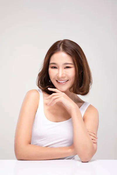 美丽的年轻亚洲女人 留着短发 一边摸着下巴 一边又高兴又快乐 有着健康而清新的皮肤 有着洁白的背景 美感十足 — 图库照片