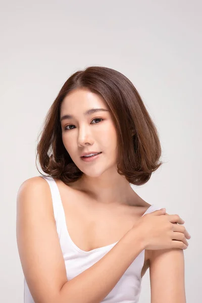 美丽的年轻亚洲女人 摸着肩膀 快乐而快乐 有着健康的洁净而新鲜的皮肤 有着灰白的背景 美容美感 — 图库照片