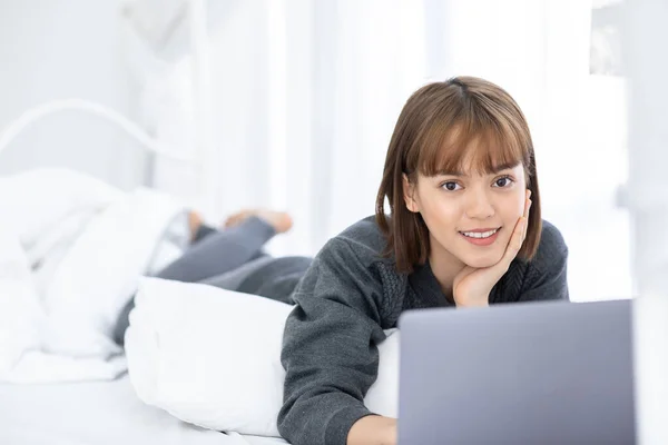 아름다운 아시아 소녀가 침대에 미디어를 사용하고 쇼핑을 컴퓨터 랩탑을 사용하는 — 스톡 사진