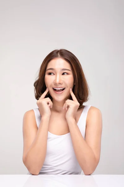 きれいな肌と新鮮な肌で柔らかい頬の笑顔に触れる美しいアジアの若い女性幸福と陽気な肯定的な感情で 灰色の背景に隔離された 美容と化粧品の概念 — ストック写真