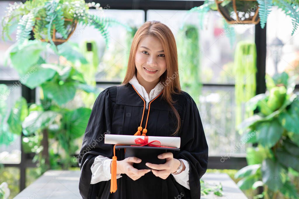 Beautiful Attractive Asian graduation woman in gown holding graduation cap and certificated so proud and happiness for finish graduate,Education Success Concept 