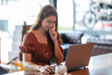 Bilgisayarlı dizüstü bilgisayarla çalışan Asyalı güzel bir kadın iş hayatında fikir ve gereksinim edinmeyi düşünüyor.