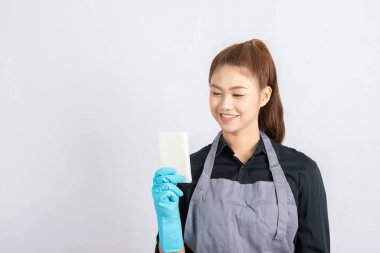 Güzel Asyalı hizmetçi gülümsemesi ve temizlik için sünger tutması çok mutlu ve kendinden emin, gri arka planda soyutlanmış, Hizmetçi Temizlik Hizmetleri Konsepti