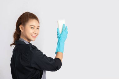 Güzel Asyalı hizmetçi gülümsemesi ve temizlik için sünger tutması çok mutlu ve kendinden emin, gri arka planda soyutlanmış, Hizmetçi Temizlik Hizmetleri Konsepti