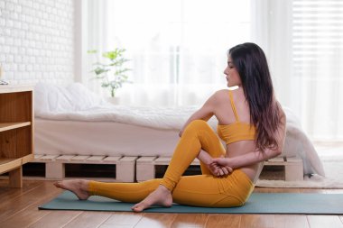 Mutlu Atletik Asyalı kadın, sabah uyandıktan sonra meditasyon gülümsemesiyle ısınmak için kaslarını esnetme hareketi yapıyor. Kendini çok rahat ve rahat hissediyor.