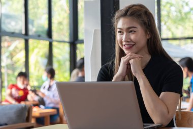 Bilgisayarlı dizüstü bilgisayarla çalışan Asyalı güzel bir kadın iş hayatında fikir ve gereksinim edinmeyi düşünüyor.