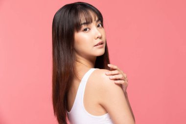 Genç ve güzel Asyalı kadın gülümsüyor omuzlarına dokunuyor temiz ve taze tenli mutluluk ve neşeli, olumlu duygusal, pembe arka planda izole edilmiş güzellik kozmetik ve kaplıca konsepti