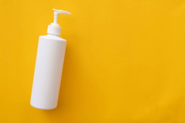 Sarı arka planda düzleşmiş kozmetik ürünleri, boş beyaz şişe losyonlarının üst görünümü yaz tatiline hazır güneş ışığı, Güzellik Konsepti