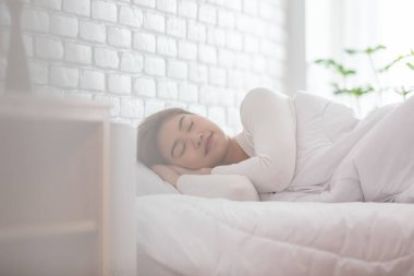 Pijama giyen güzel Asyalı kadın gözlerini kapar, gülümser ve tatlı rüyalar görür. Sabah yatak odasında rahat ve rahat hisseder. Sağlık ve Uyku Konsepti.