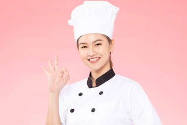 Güzel Asyalı aşçı kadın gülümse ve pembe arka planda izole edilmiş el işareti yap. Mutluluk ve neşeli profesyonel şef kavramı.